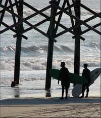 Bald Head Island surfers under a pier hunting for the *perfect* wave.