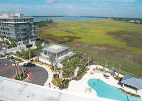 Photo of Tides condominium complex in Mt Pleasant from the air showing the building and nearby pool with marshland in the background